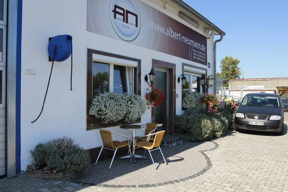 Eingangsbereich der Albert Neumann GmbH mit Firmenschild, Blumen und Sitzgelegenheit